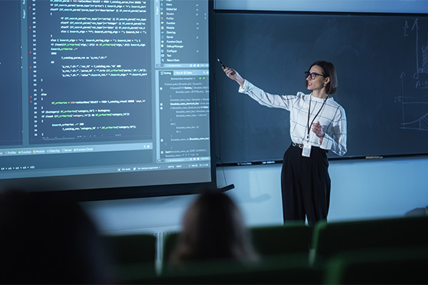 a presenter stands next to a projection screen